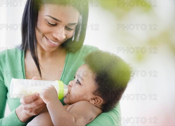 African American mother feeding bottle to baby boy