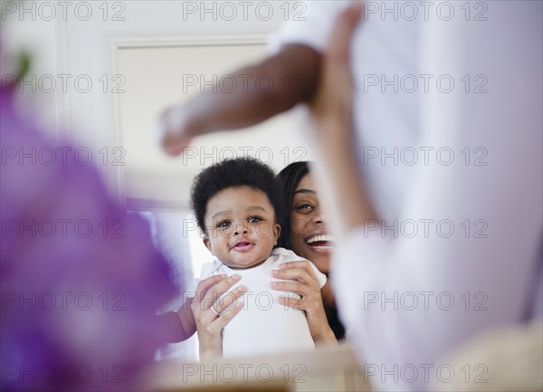 African American mother holding son up in mirror