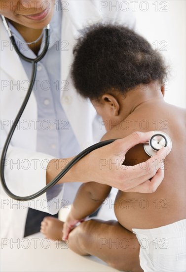 African American doctor listening to baby's breathing