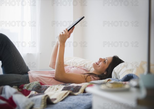 Brazilian woman using digital tablet in bed