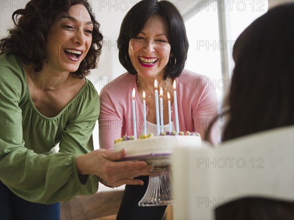 Grandmother and mother giving birthday cake to daughter