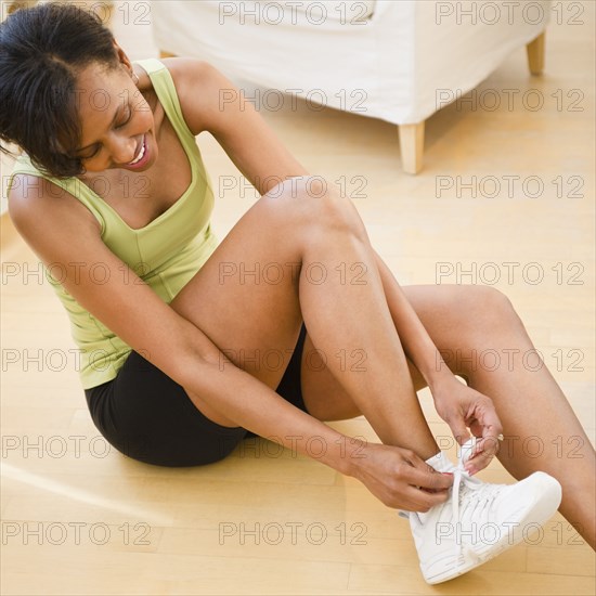 Black woman putting on athletic shoes