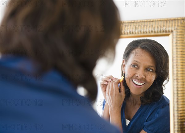 Black woman putting on earrings