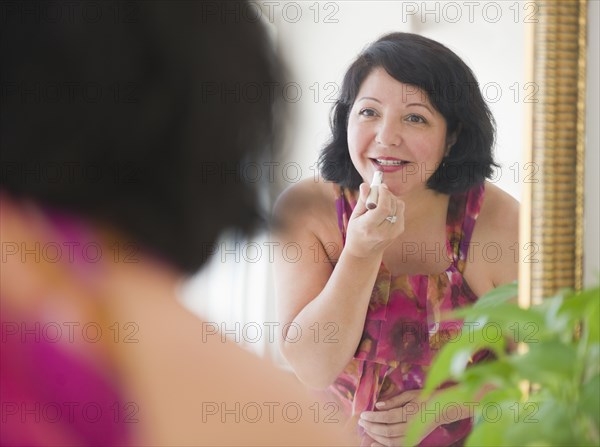 Hispanic woman putting on lipstick