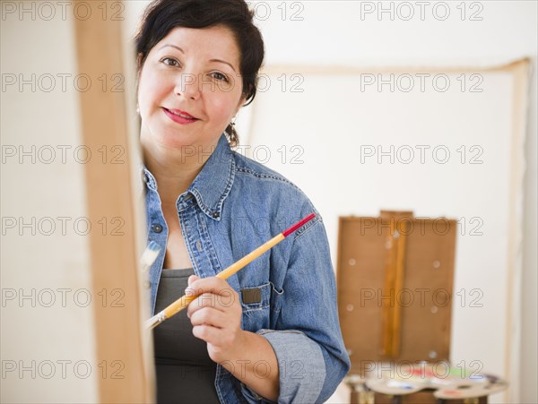 Hispanic woman painting on canvas