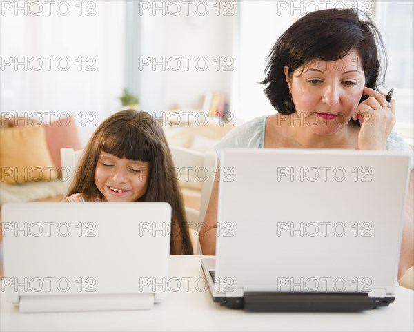 Hispanic mother and daughter using laptops