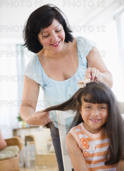 Hispanic woman brushing daughter's hair
