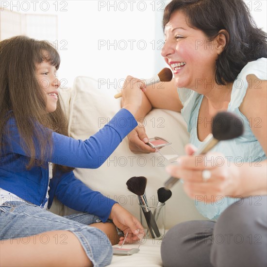 Hispanic mother and daughter putting on makeup