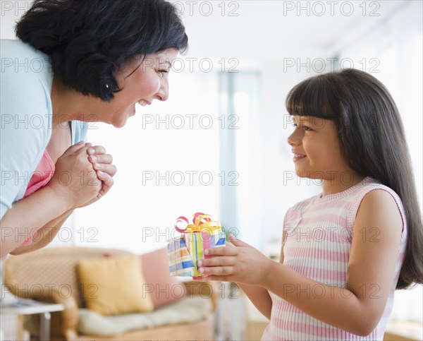 Hispanic girl giving her mother birthday gift