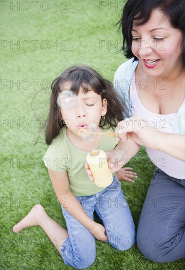 Hispanic mother and daughter blowing bubbles