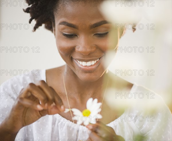 Black woman plucking petals from daisy