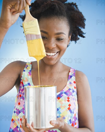 Black woman holding paintbrush dripping paint