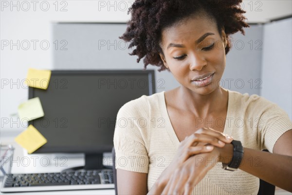 Black businesswoman checking the time at desk