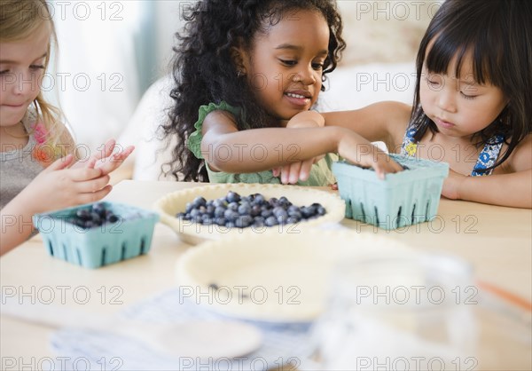 Girls putting blueberries into bowl together