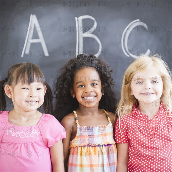 Smiling girls standing near blackboard