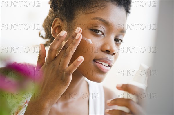 Black woman putting on face lotion