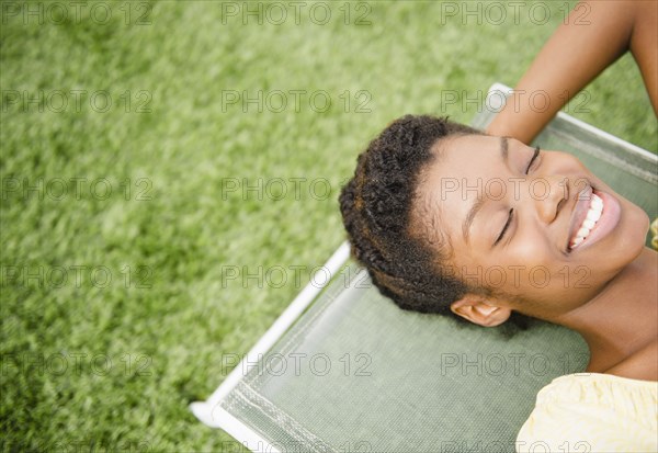 Smiling Black woman laying on deck chair