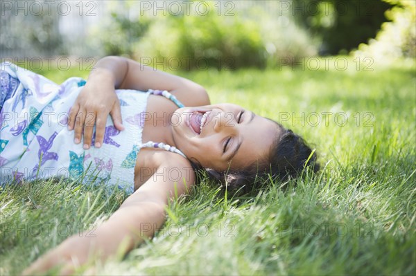 Laughing Hispanic girl laying in grass