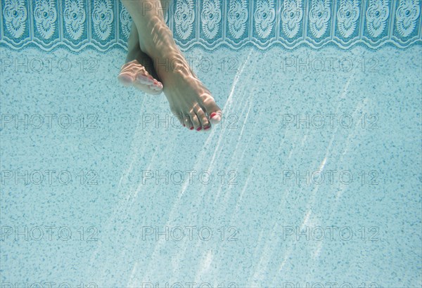 Caucasian woman's feet underwater in swimming pool