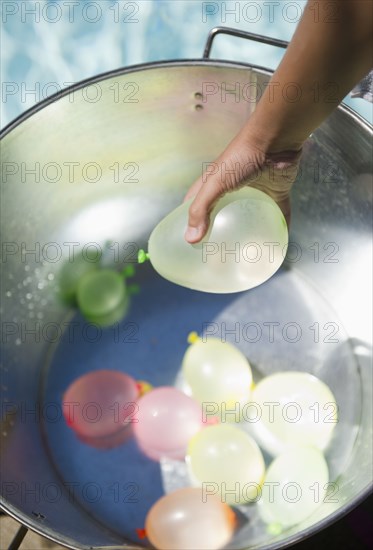 Hispanic girl picking water balloon out of bucket