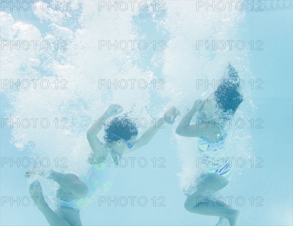 Hispanic girls jumping into swimming pool