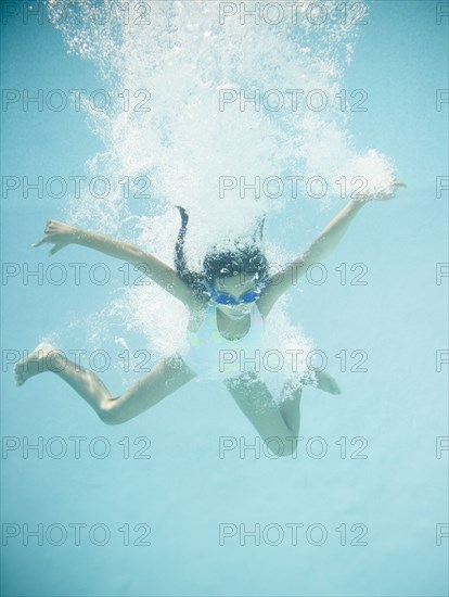 Hispanic girl jumping into swimming pool