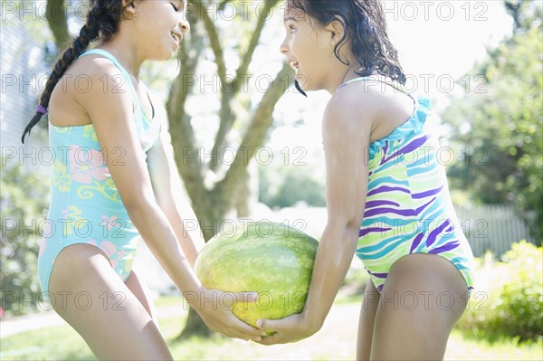 Hispanic girls carrying watermelon together