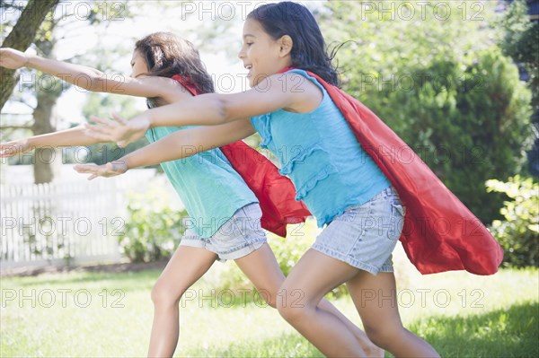 Hispanic girls in capes playing superheroes