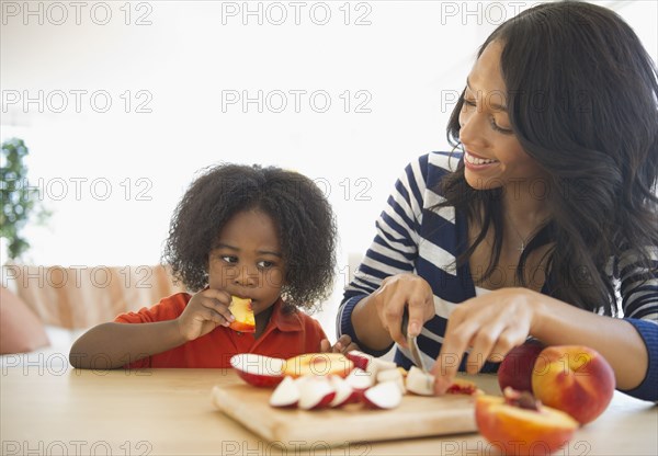 African American mother cutting fruit for son