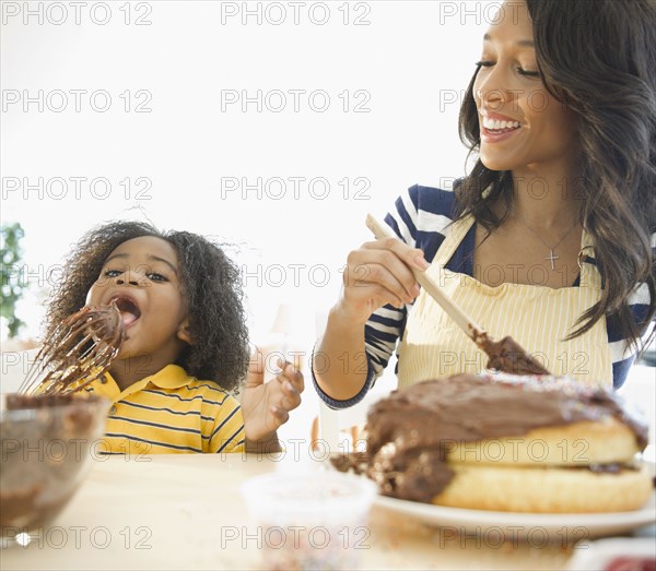 African American mother watching son licking cake icing