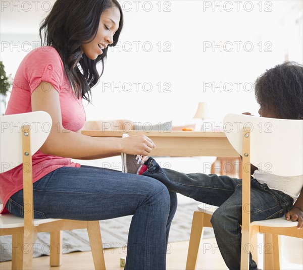 African American woman tying son's shoes