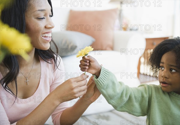 African American boy giving mother flower