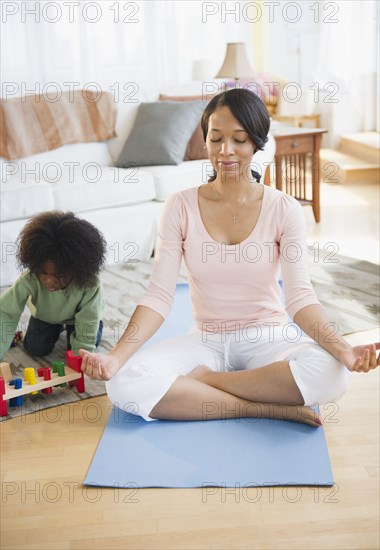 African American mother practicing yoga while son plays