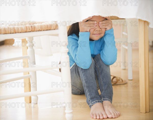 Korean girl hiding underneath table