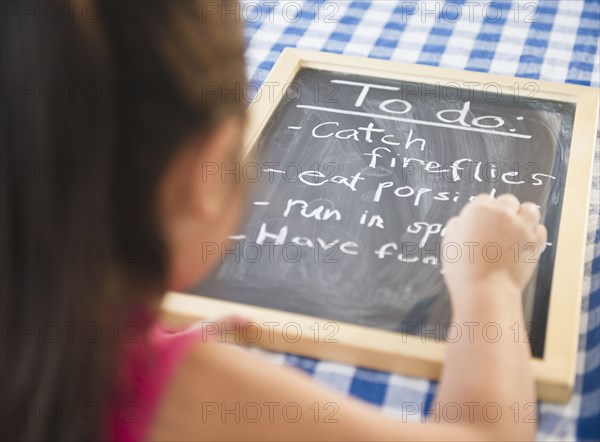 Korean girl writing to do list on blackboard