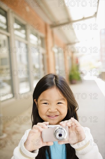 Korean girl taking photographs with digital camera