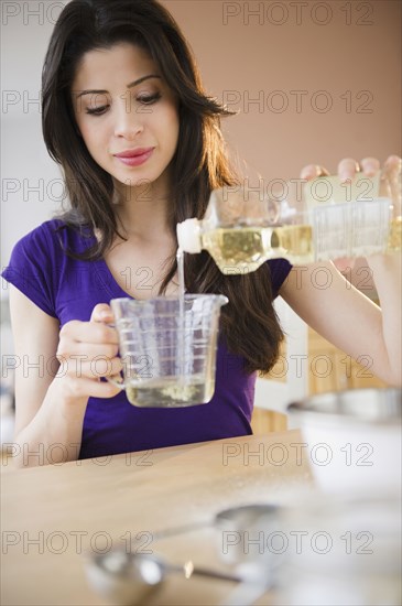 Mixed race woman measuring cooking oil