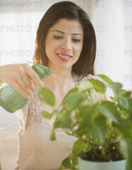 Mixed race woman watering plant