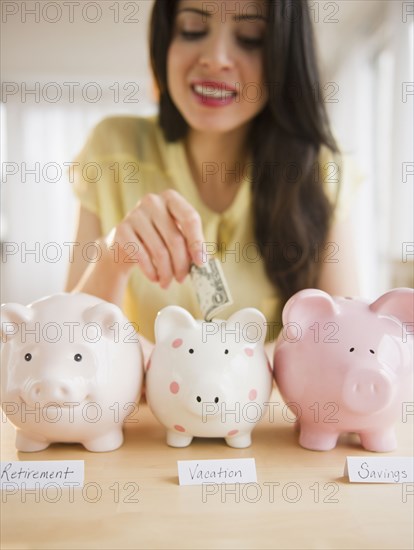 Mixed race woman putting money into piggy bank