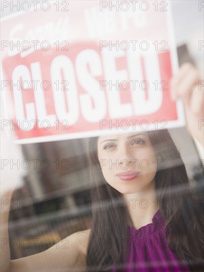 Mixed race woman putting up closed sign