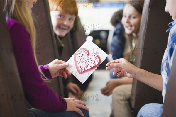 Girl giving friend Valentine on school bus