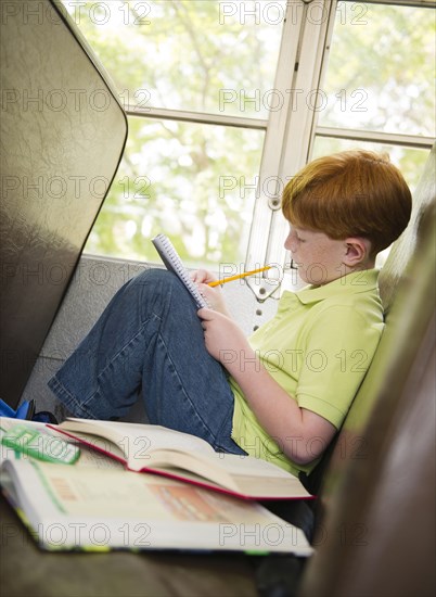 Caucasian boy doing homework on school bus