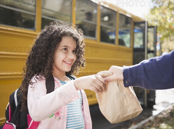 Mother handing daughter sack lunch