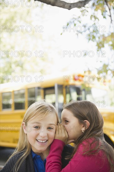 Caucasian girls whispering while waiting for school bus