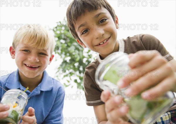 Boys holding jars catching bugs