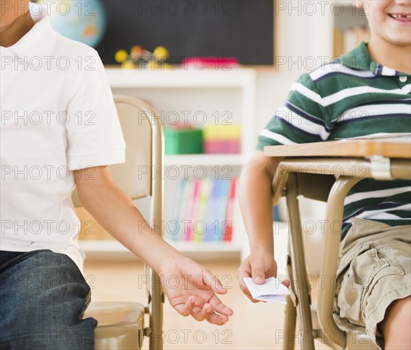 Boys passing note in classroom