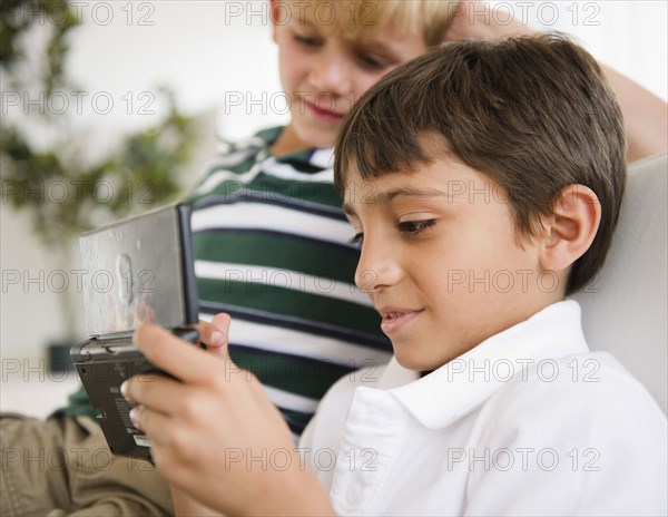 Boy watching friend playing hand-held video game