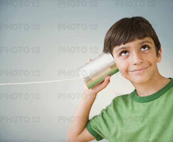 Hispanic boy listening to tin can telephone