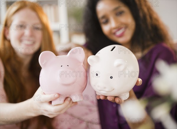 Friends holding piggy banks