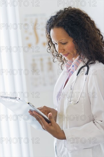 Hispanic doctor looking at medical chart in hospital